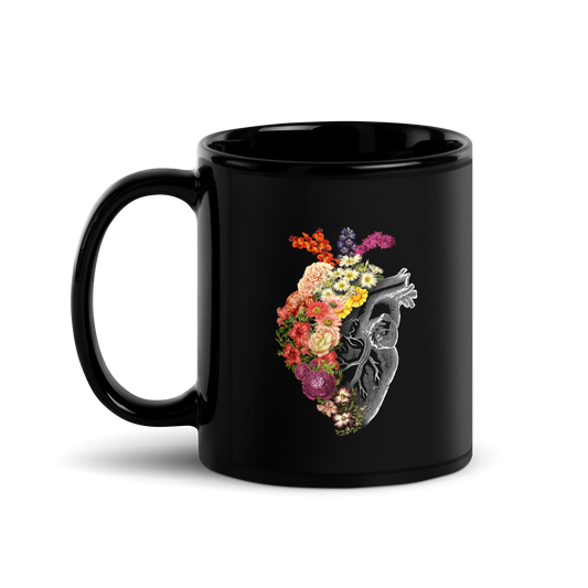 The design is an intricate and anatomical drawing of a human heart on a black background. The left side of the heart morphs into a vibrant assortment of colorful flowers, including roses, daisies, and other blooming blossoms, creating a striking contrast between the realistic and the surreal, symbolizing the harmony between nature and humanity.