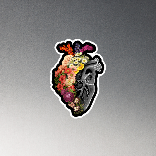 The design is an intricate and anatomical drawing of a human heart on a black background. The left side of the heart morphs into a vibrant assortment of colorful flowers, including roses, daisies, and other blooming blossoms, creating a striking contrast between the realistic and the surreal, symbolizing the harmony between nature and humanity.