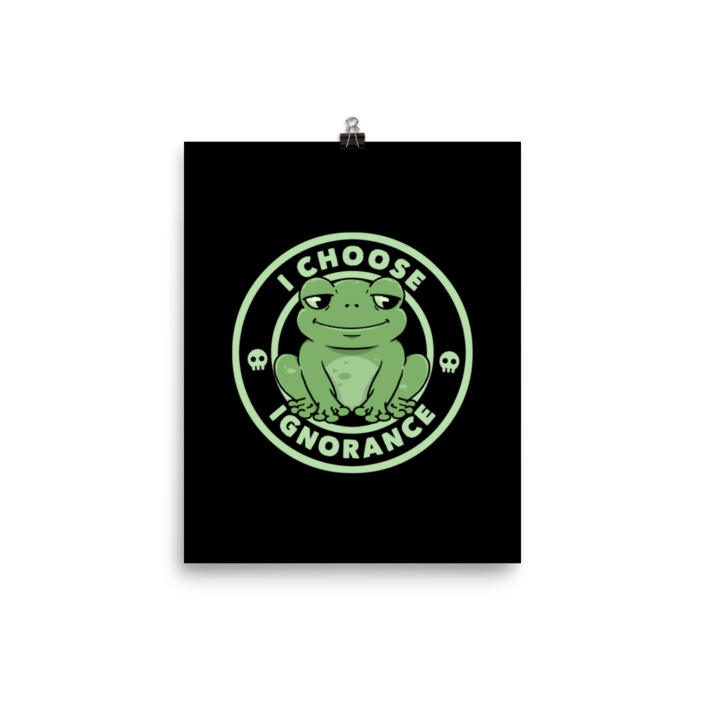 The image shows a cartoonish green frog with a sly smile, sitting with legs splayed out. Around it, the phrase 'I CHOOSE IGNORANCE' is written in bold letters. Two small skull designs are included, one on each side of the frog. The style is playful and ironic, blending elements of humor and rebellion.