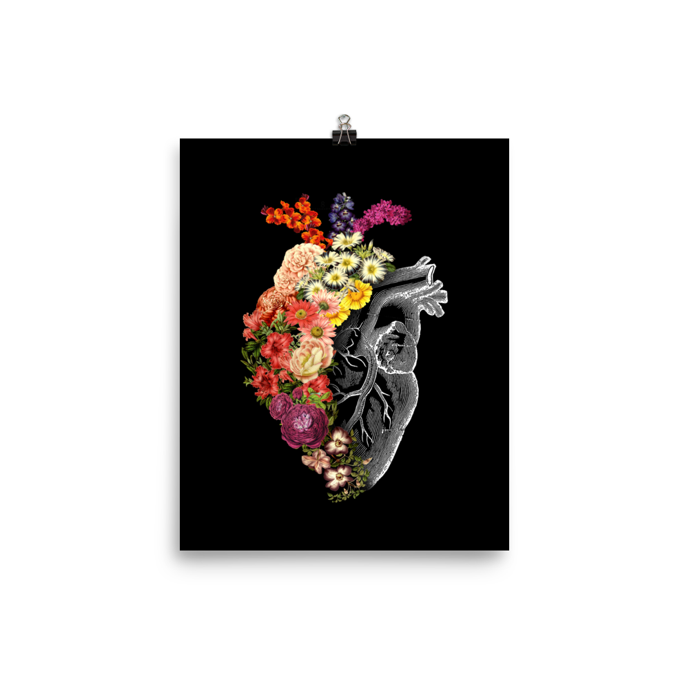 The design is an intricate and anatomical drawing of a human heart on a black background. The left side of the heart morphs into a vibrant assortment of colorful flowers, including roses, daisies, and other blooming blossoms, creating a striking contrast between the realistic and the surreal, symbolizing the harmony between nature and humanity.