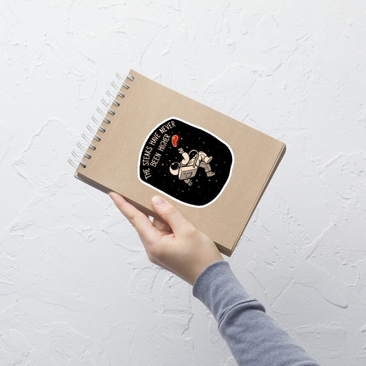 An astronaut floating through space with a small steak in front of him, paired with the phrase ‘The Steaks Have Never Been Higher’. A playful and humorous design that blends space exploration with a clever visual pun. Perfect for fans of witty wordplay and quirky art.