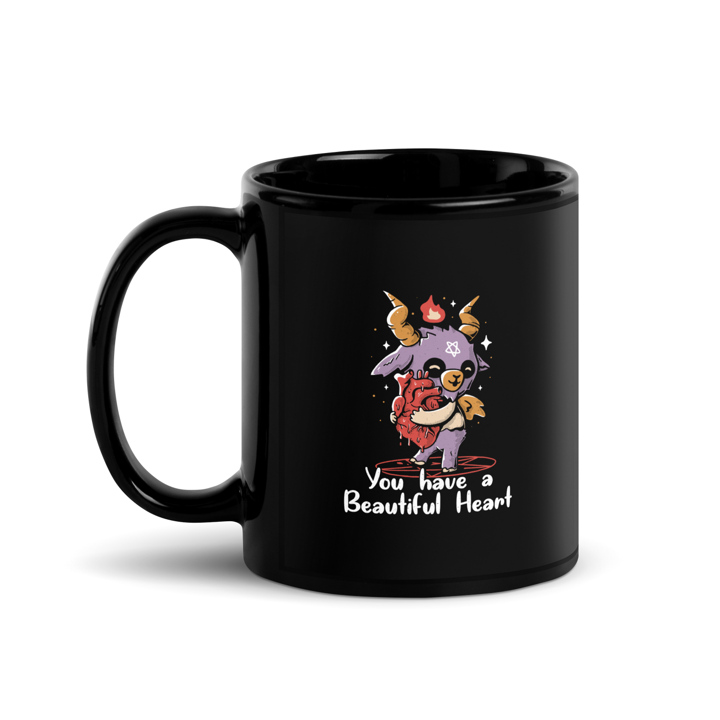 The design features a cute, cartoonish, anthropomorphic goat with big horns and a flame above its head, standing on a red pentagram. The goat has a star on its forehead and is hugging a large, anatomically correct human heart. The text below reads, 'You have a Beautiful Heart'. The image combines elements of occult symbolism with a playful, endearing aesthetic.