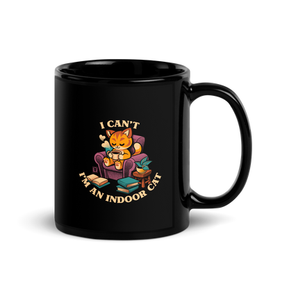 This cozy design features a contented orange cat sipping coffee in a comfy chair, surrounded by books and plants. The following message encircles the design: I CAN'T I'M AN INDOOR CAT.