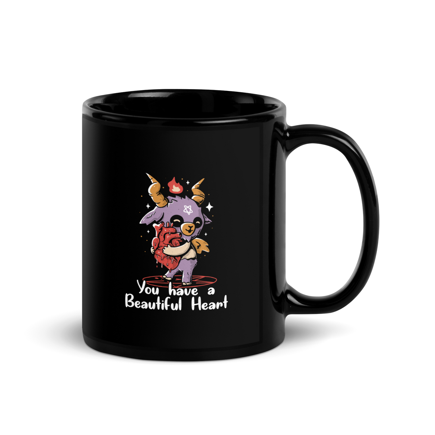 The design features a cute, cartoonish, anthropomorphic goat with big horns and a flame above its head, standing on a red pentagram. The goat has a star on its forehead and is hugging a large, anatomically correct human heart. The text below reads, 'You have a Beautiful Heart'. The image combines elements of occult symbolism with a playful, endearing aesthetic.