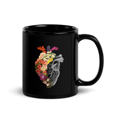 The design is an intricate and anatomical drawing of a human heart on a black background. The left side of the heart morphs into a vibrant assortment of colorful flowers, including roses, daisies, and other blooming blossoms, creating a striking contrast between the realistic and the surreal, symbolizing the harmony between nature and humanity.