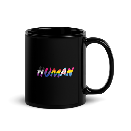 The image displays the word 'HUMAN' in bold, capitalized letters filled with colorful pride flag patterns. The colors within the letters represent different LGBTQ+ pride flags, symbolizing inclusivity and diversity. The background is solid black, which makes the colorful patterns stand out more vibrantly.