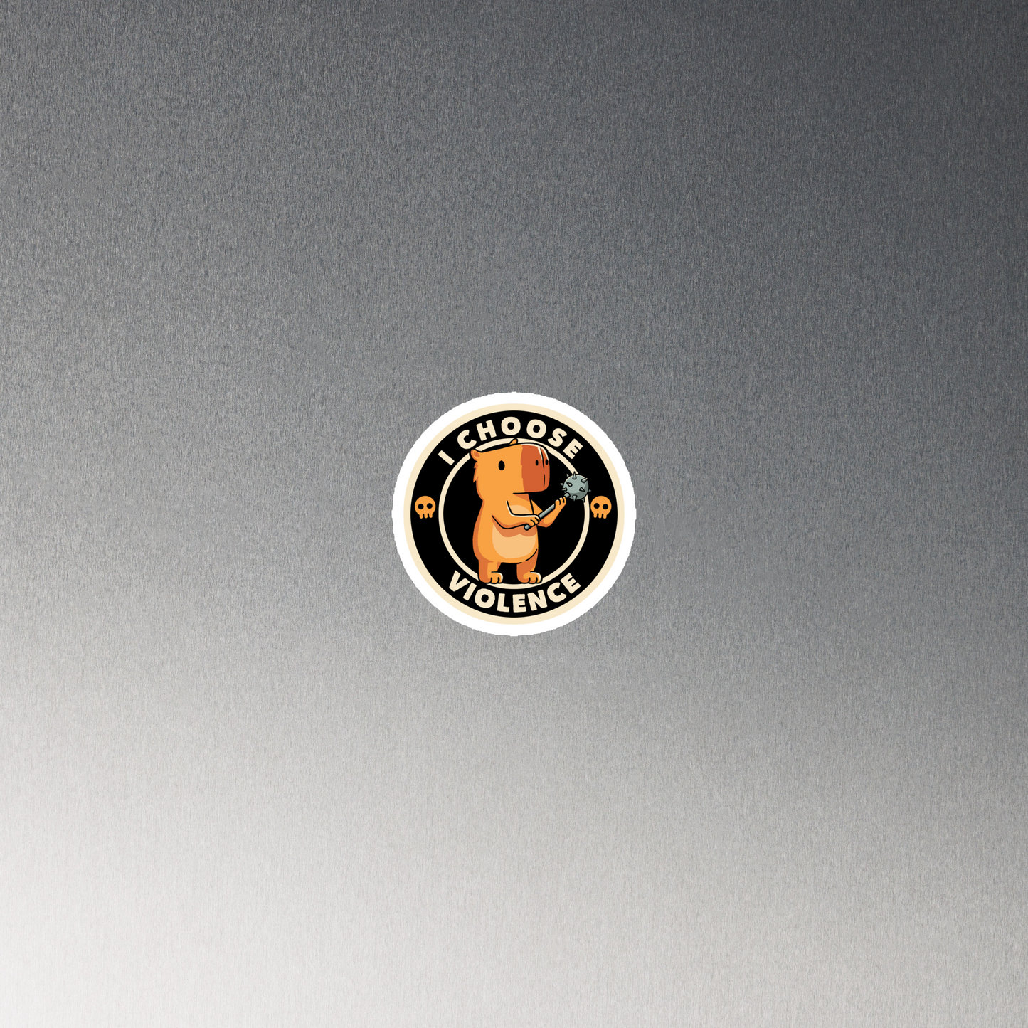 A cute, cartoonish burnt yellow capybara stands holding a spiked mace with a determined expression. Surrounding it is a circular design with the text 'I CHOOSE VIOLENCE' and two small skulls on either side, giving it a humorous yet ironic tone.