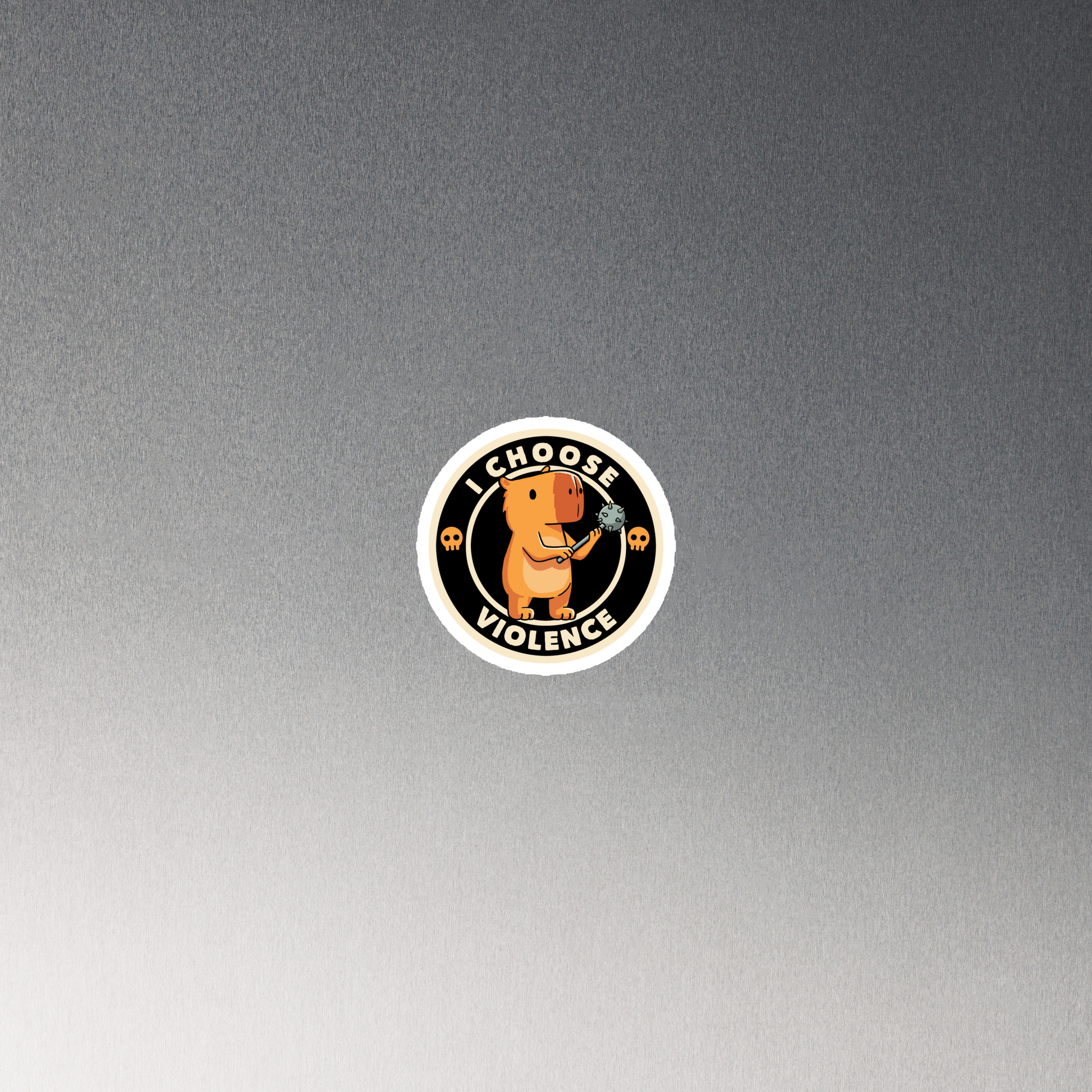 A cute, cartoonish burnt yellow capybara stands holding a spiked mace with a determined expression. Surrounding it is a circular design with the text 'I CHOOSE VIOLENCE' and two small skulls on either side, giving it a humorous yet ironic tone.