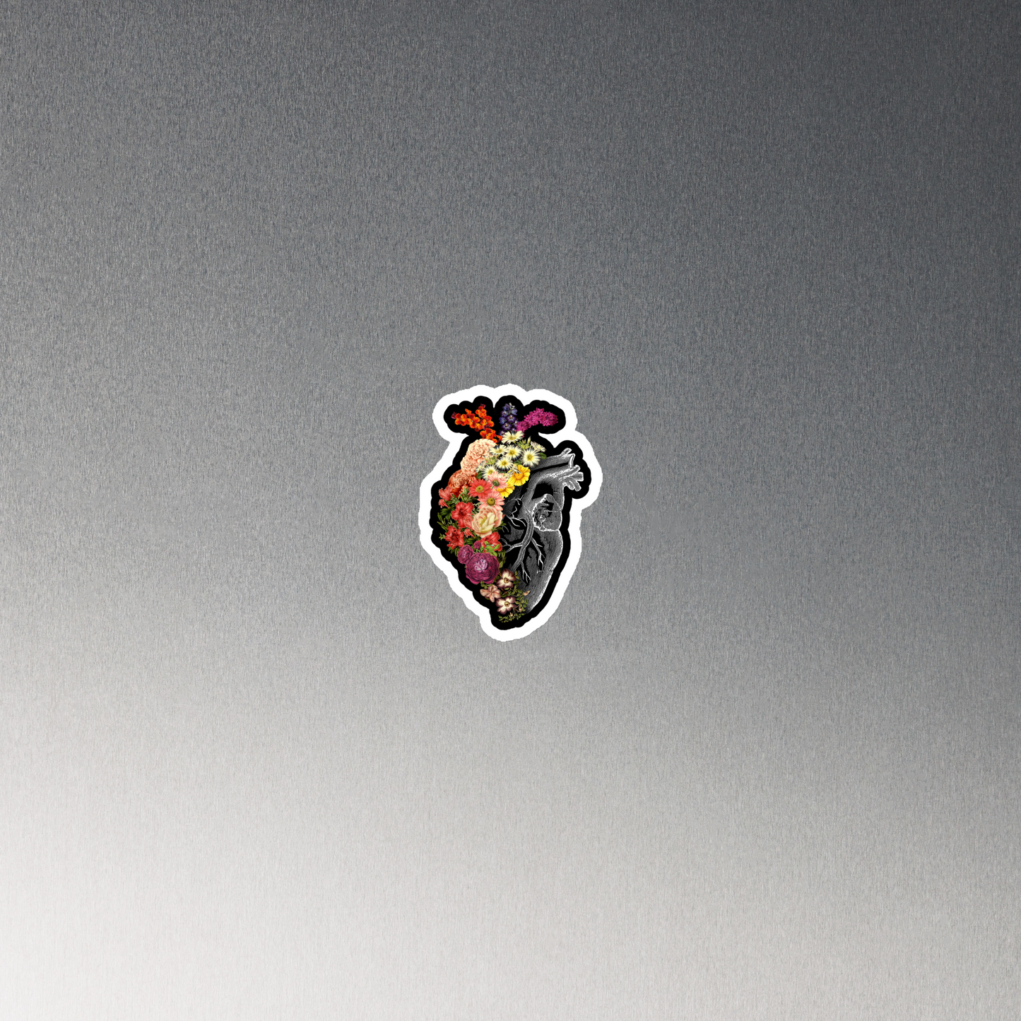 The design is an intricate and anatomical drawing of a human heart on a black background. The left side of the heart morphs into a vibrant assortment of colorful flowers, including roses, daisies, and other blooming blossoms, creating a striking contrast between the realistic and the surreal, symbolizing the harmony between nature and humanity.