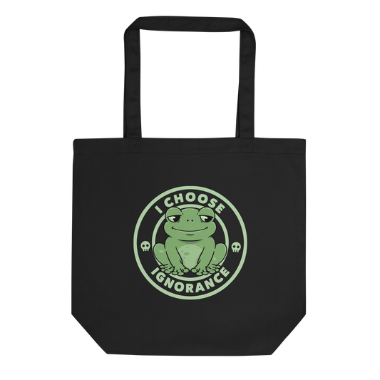 The image shows a cartoonish green frog with a sly smile, sitting with legs splayed out. Around it, the phrase 'I CHOOSE IGNORANCE' is written in bold letters. Two small skull designs are included, one on each side of the frog. The style is playful and ironic, blending elements of humor and rebellion.