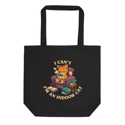 This cozy design features a contented orange cat sipping coffee in a comfy chair, surrounded by books and plants. The following message encircles the design: I CAN'T I'M AN INDOOR CAT.