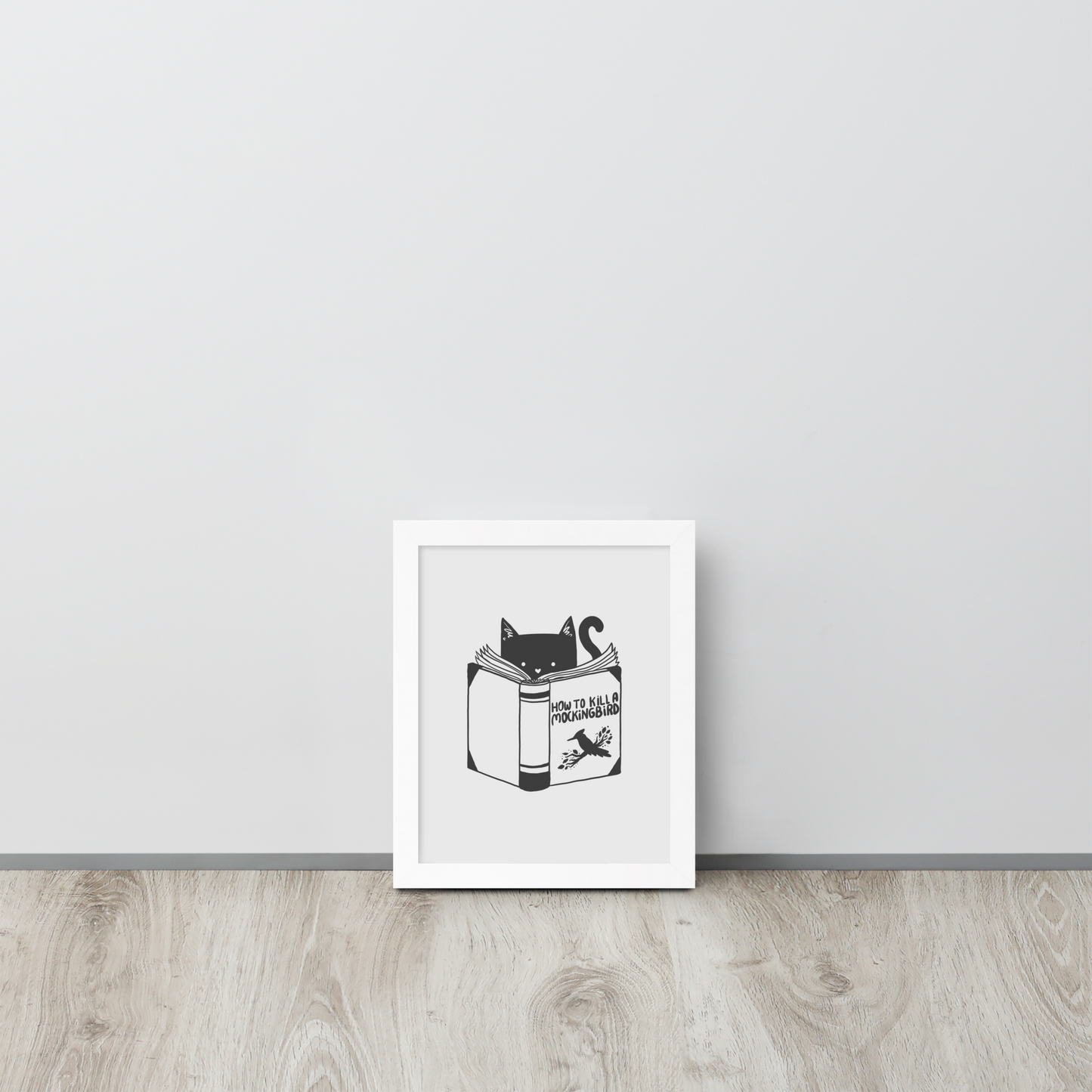 A black and white illustration features a cat peeking over an open book titled 'How to Kill a Mockingbird,' playfully altering the classic novel's title. The cat has a heart-shaped nose and simple, cute facial features. The design is whimsical and ironic, combining classic literature with a humorous twist.