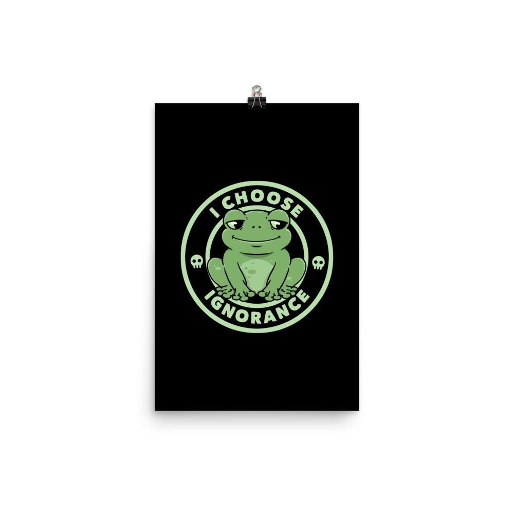 The image shows a cartoonish green frog with a sly smile, sitting with legs splayed out. Around it, the phrase 'I CHOOSE IGNORANCE' is written in bold letters. Two small skull designs are included, one on each side of the frog. The style is playful and ironic, blending elements of humor and rebellion.