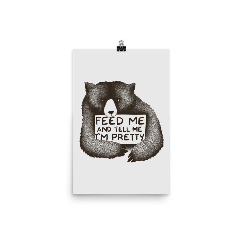 This drawing is of a cute, cartoon-style bear holding a sign with a heart-shaped nose and simple, expressive eyes. The sign reads, 'Feed me and tell me I'm pretty' in a handwritten, playful font. The bear's fur is detailed with fine, textured lines, giving it a cozy, endearing look. The drawing has a monochrome, black-and-white color scheme