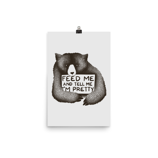 This drawing is of a cute, cartoon-style bear holding a sign with a heart-shaped nose and simple, expressive eyes. The sign reads, 'Feed me and tell me I'm pretty' in a handwritten, playful font. The bear's fur is detailed with fine, textured lines, giving it a cozy, endearing look. The drawing has a monochrome, black-and-white color scheme