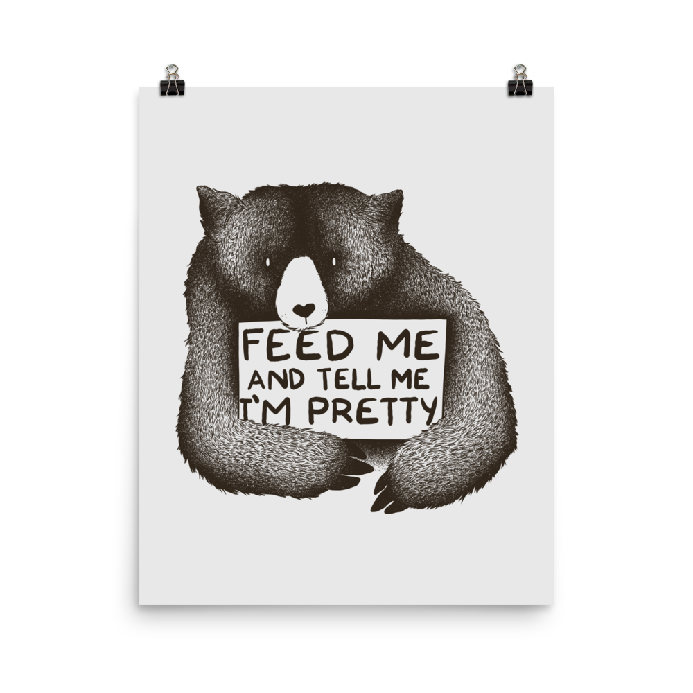 This drawing is of a cute, cartoon-style bear holding a sign with a heart-shaped nose and simple, expressive eyes. The sign reads, 'Feed me and tell me I'm pretty' in a handwritten, playful font. The bear's fur is detailed with fine, textured lines, giving it a cozy, endearing look. The drawing has a monochrome, black-and-white color scheme