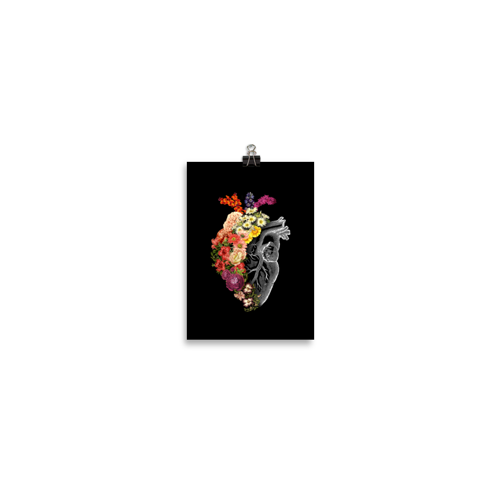 The design is an intricate and anatomical drawing of a human heart on a black background. The left side of the heart morphs into a vibrant assortment of colorful flowers, including roses, daisies, and other blooming blossoms, creating a striking contrast between the realistic and the surreal, symbolizing the harmony between nature and humanity.