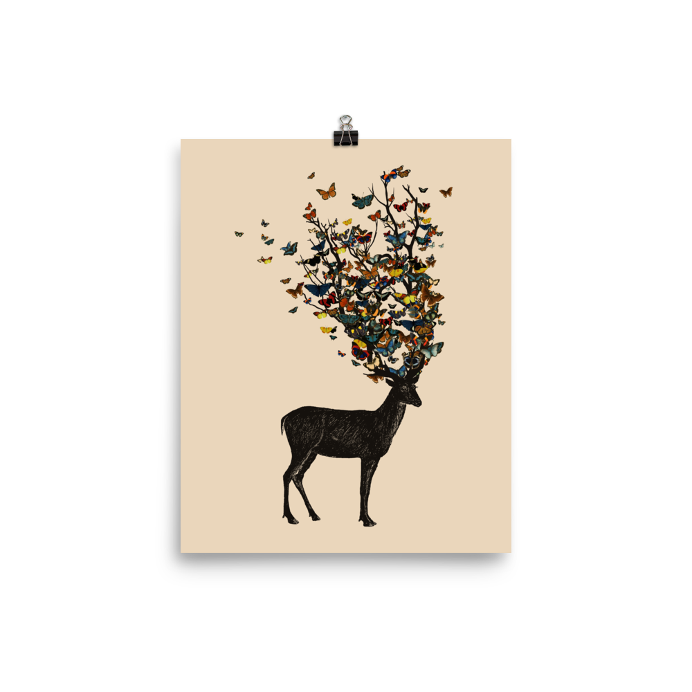 The image depicts a dark, silhouetted deer standing on a neutral background. Instead of branches, its antlers transform into a swirling cloud of vibrant, colorful butterflies that extend upwards and outward. The mix of organic and ethereal elements creates a captivating and whimsical visual contrast.