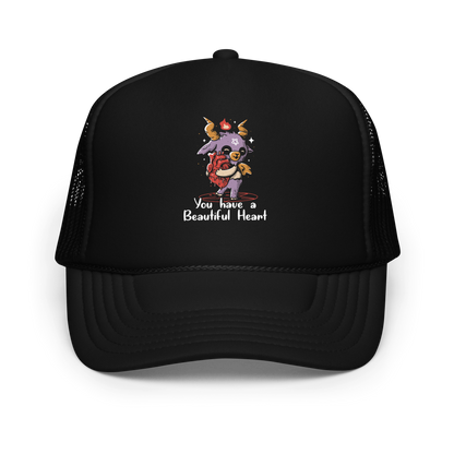 The design features a cute, cartoonish, anthropomorphic goat with big horns and a flame above its head, standing on a red pentagram. The goat has a star on its forehead and is hugging a large, anatomically correct human heart. The text below reads, 'You have a Beautiful Heart'. The image combines elements of occult symbolism with a playful, endearing aesthetic.