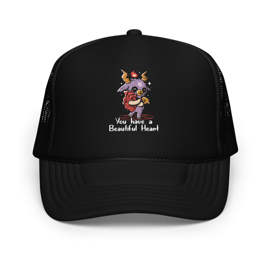 The design features a cute, cartoonish, anthropomorphic goat with big horns and a flame above its head, standing on a red pentagram. The goat has a star on its forehead and is hugging a large, anatomically correct human heart. The text below reads, 'You have a Beautiful Heart'. The image combines elements of occult symbolism with a playful, endearing aesthetic.