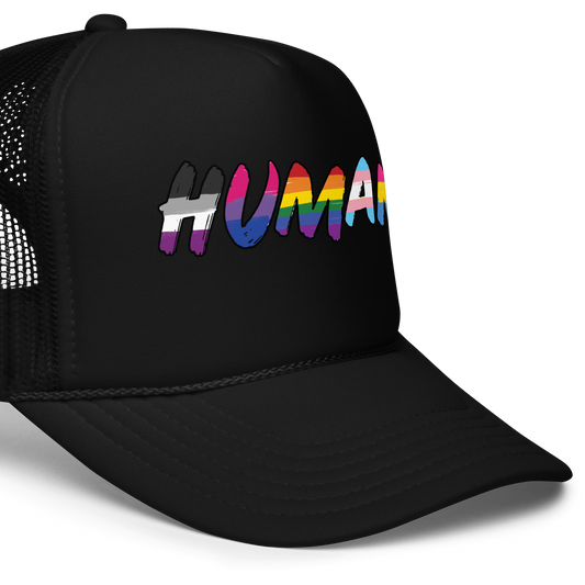 The image displays the word 'HUMAN' in bold, capitalized letters filled with colorful pride flag patterns. The colors within the letters represent different LGBTQ+ pride flags, symbolizing inclusivity and diversity. The background is solid black, which makes the colorful patterns stand out more vibrantly.