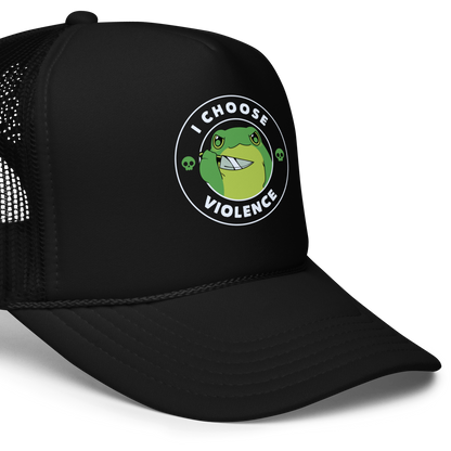 A charming, cartoon-style green frog holds a knife in its hand with a playful yet fierce expression. Encircled by bold text, 'I CHOOSE VIOLENCE,' the design mixes humor with an edge. Two small skulls flank the frog, adding a quirky, rebellious touch to the image. The overall effect balances cuteness and irony in a memorable way.