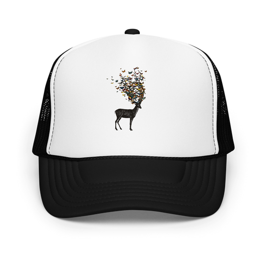 The image depicts a dark, silhouetted deer standing on a neutral background. Instead of branches, its antlers transform into a swirling cloud of vibrant, colorful butterflies that extend upwards and outward. The mix of organic and ethereal elements creates a captivating and whimsical visual contrast.