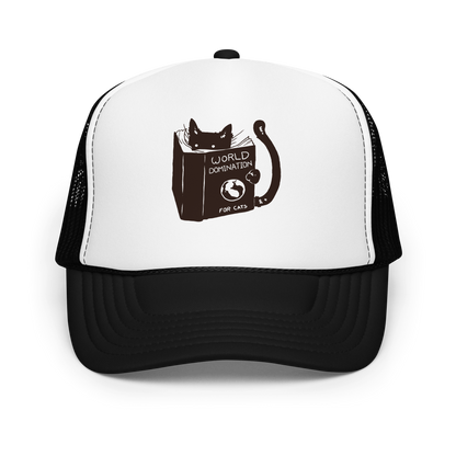 The design features a black silhouette of a cat peeking from behind an oversized book. The book's cover reads 'World Domination for Cats,' and includes a simple drawing of a globe. The cat's eyes are wide open, suggesting either surprise or intense focus on its 'world domination' plans.