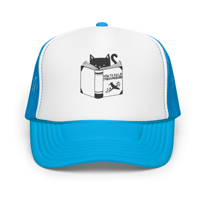 A black and white illustration features a cat peeking over an open book titled 'How to Kill a Mockingbird,' playfully altering the classic novel's title. The cat has a heart-shaped nose and simple, cute facial features. The design is whimsical and ironic, combining classic literature with a humorous twist.