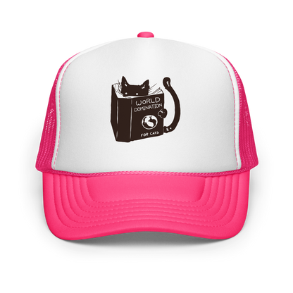 The design features a black silhouette of a cat peeking from behind an oversized book. The book's cover reads 'World Domination for Cats,' and includes a simple drawing of a globe. The cat's eyes are wide open, suggesting either surprise or intense focus on its 'world domination' plans.