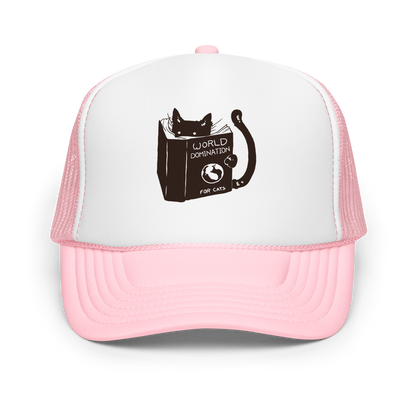 The design features a black silhouette of a cat peeking from behind an oversized book. The book's cover reads 'World Domination for Cats,' and includes a simple drawing of a globe. The cat's eyes are wide open, suggesting either surprise or intense focus on its 'world domination' plans.