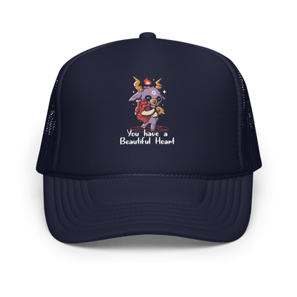 The design features a cute, cartoonish, anthropomorphic goat with big horns and a flame above its head, standing on a red pentagram. The goat has a star on its forehead and is hugging a large, anatomically correct human heart. The text below reads, 'You have a Beautiful Heart'. The image combines elements of occult symbolism with a playful, endearing aesthetic.