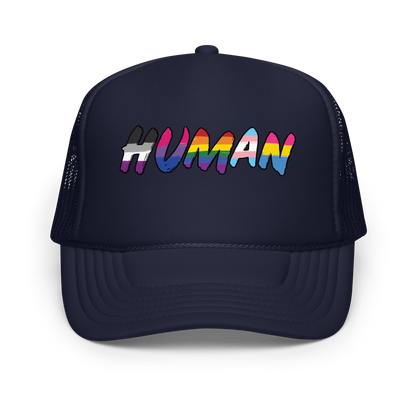 The image displays the word 'HUMAN' in bold, capitalized letters filled with colorful pride flag patterns. The colors within the letters represent different LGBTQ+ pride flags, symbolizing inclusivity and diversity. The background is solid black, which makes the colorful patterns stand out more vibrantly.