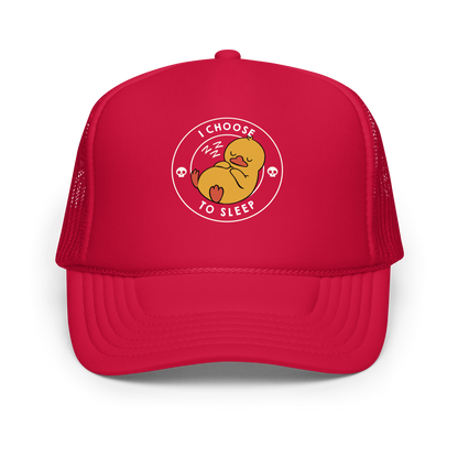 A cute, cartoonish yellow duck is peacefully sleeping with a contented expression. Its webbed feet and wings are tucked in. Around it, the words 'I Choose to Sleep' are inscribed in white letters. Two small skulls accompany this text, adding a humorous, edgy touch. The design is simple, charming, and playful, appealing to fans of ironic, whimsical art.