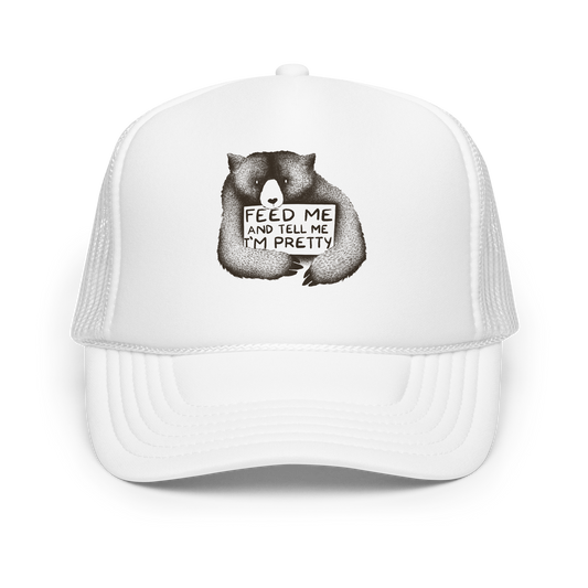 This drawing is of a cute, cartoon-style bear holding a sign with a heart-shaped nose and simple, expressive eyes. The sign reads, 'Feed me and tell me I'm pretty' in a handwritten, playful font. The bear's fur is detailed with fine, textured lines, giving it a cozy, endearing look. The drawing has a monochrome, black-and-white color scheme