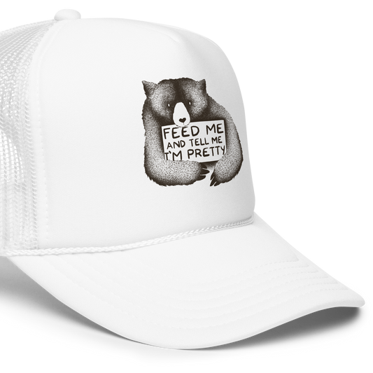 This drawing is of a cute, cartoon-style bear holding a sign with a heart-shaped nose and simple, expressive eyes. The sign reads, 'Feed me and tell me I'm pretty' in a handwritten, playful font. The bear's fur is detailed with fine, textured lines, giving it a cozy, endearing look. The drawing has a monochrome, black-and-white color scheme