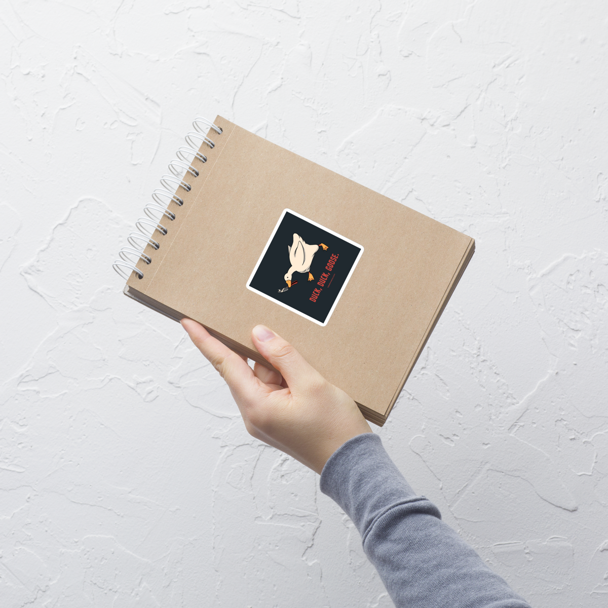 A white goose gripping a sharp knife in its beak with the phrase “Duck, Duck, Goose” below. A playful twist on the classic game, this design captures chaotic goose energy with a sharp dose of dark humor.