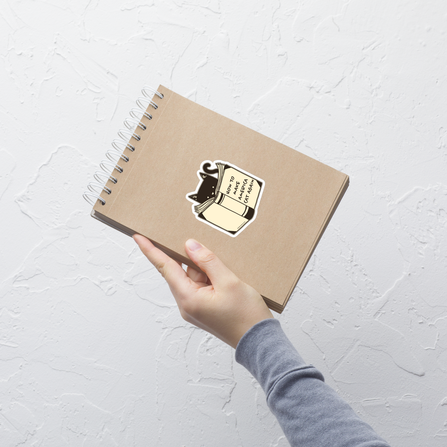 A minimalist illustration of a cat reading a book titled “How to Make America Cat Again”. A clean, witty design that blends feline charm with ironic humor, perfect for cat lovers and fans of clever, minimalist art.