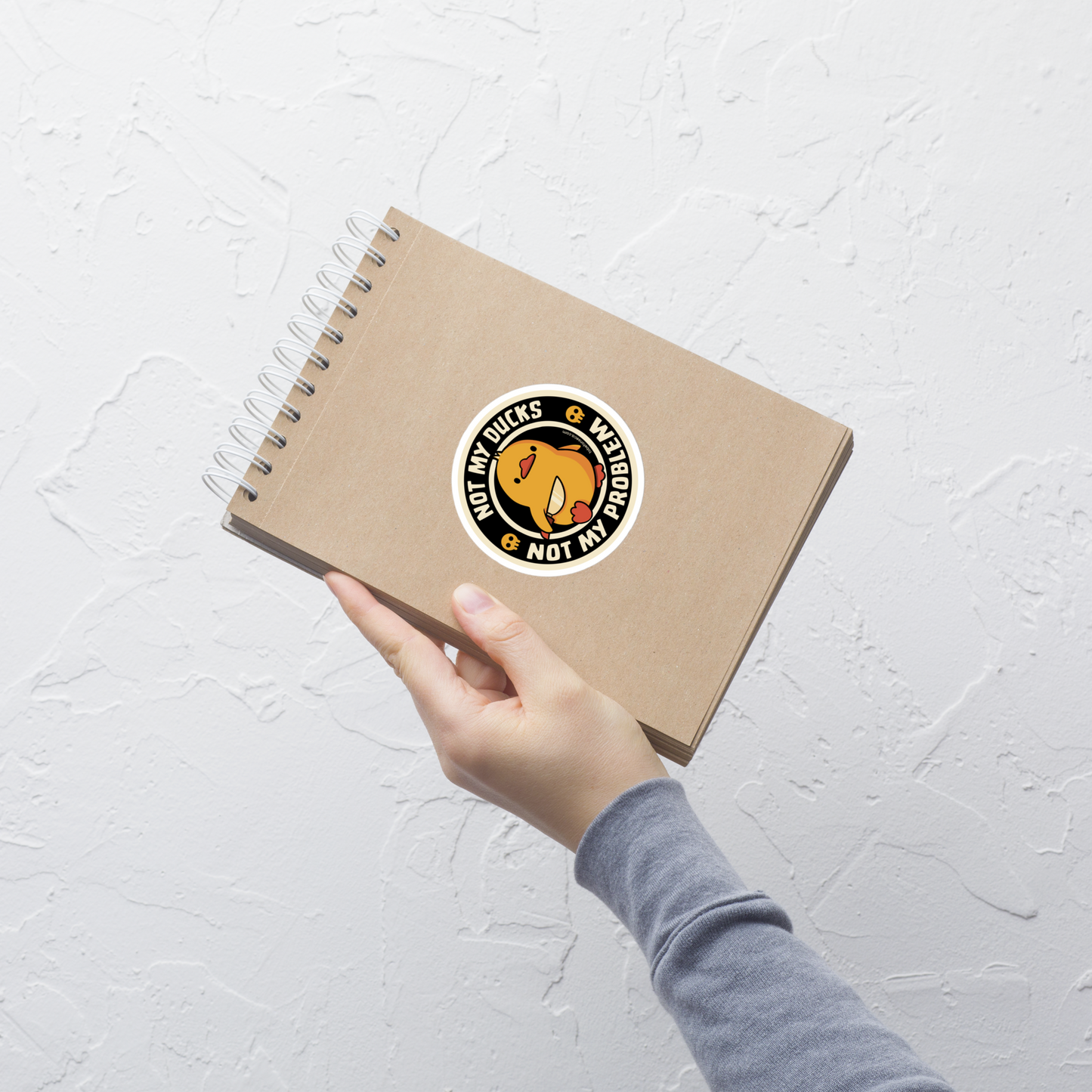 A cute yellow duck holding a tiny knife with an unexpectedly fierce attitude. Around it, the phrase "Not My Ducks Not My Problem" adds a sarcastic twist to the sweet but chaotic vibe. A playful design that blends humor, duck drama, and a touch of unapologetic mischief, perfect for fans of witty, slightly unhinged art.