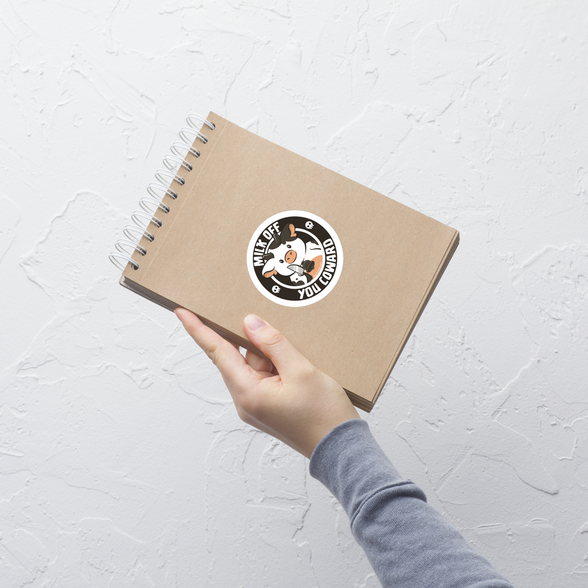 A quirky stamp-style design featuring a cute spotted cow holding a knife alongside the phrase "Milk Off You Coward". Blending dark humour with a cheeky attitude, this playful design is perfect for cow lovers, fans of sarcastic humour, and anyone who enjoys bold, irreverent artwork.