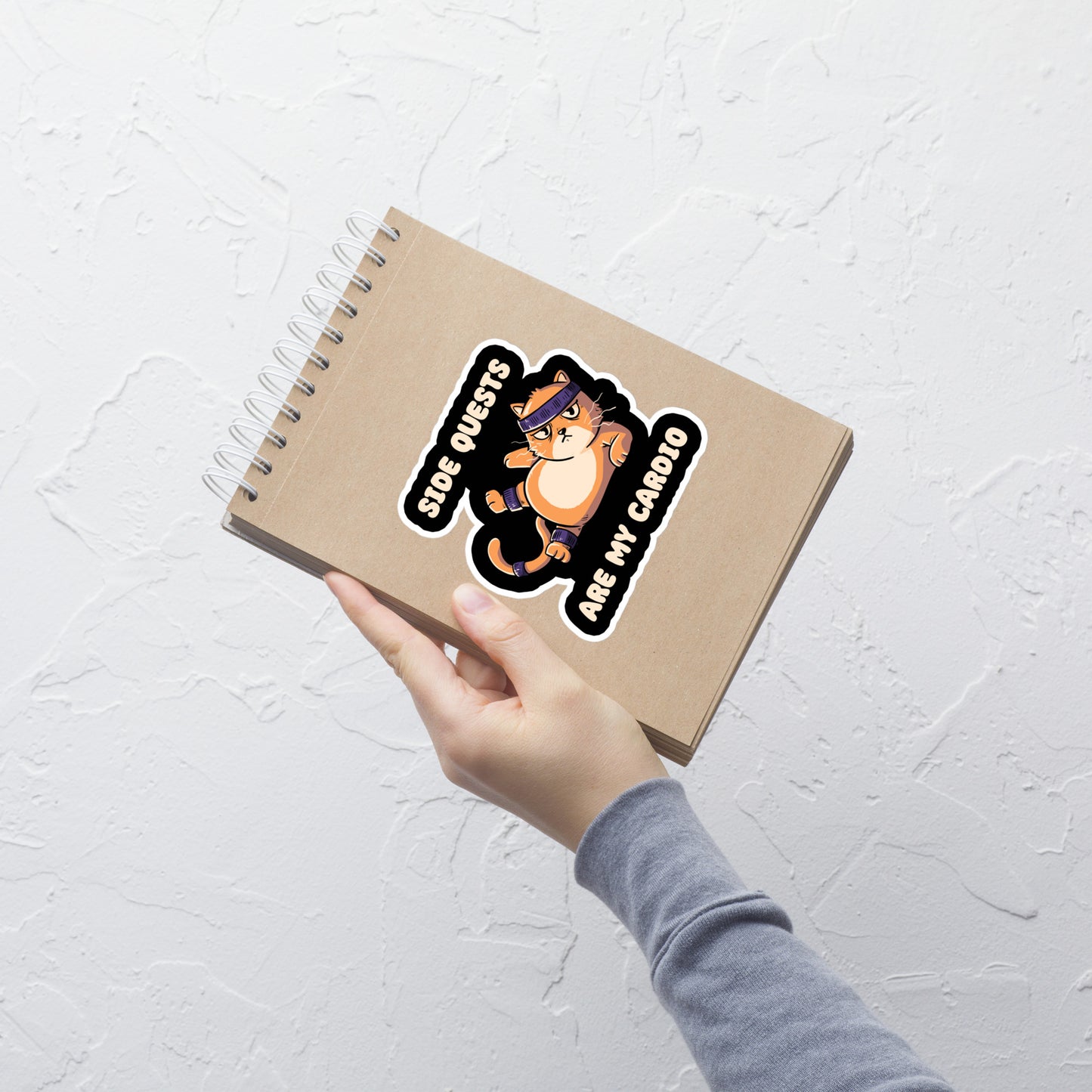 An orange kitten in gym clothes doing an aerobic workout, paired with the phrase ‘Side Quests Are My Cardio Gym Cat’. A humorous design that mixes cats, gaming vibes and fitness irony, perfect for those who prefer playful side quests over serious workouts.