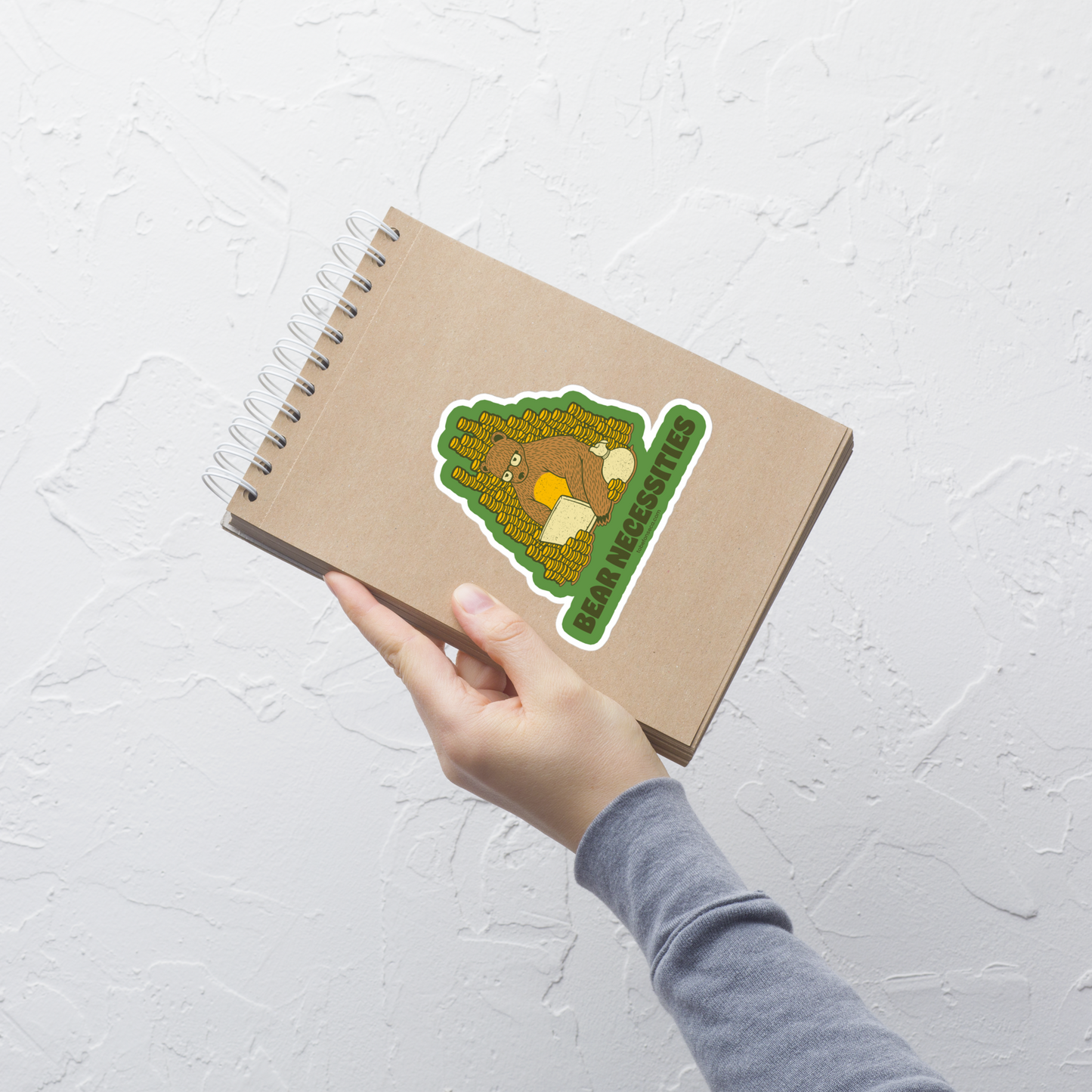 A brown bear wearing glasses works on his laptop, surrounded by stacks of coins. The phrase ‘Bear Necessities’ adds a clever, humorous twist. A minimalist and playful design, perfect for entrepreneurs, freelancers, office lovers and fans of witty animal art.