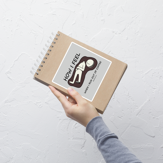 A minimalist doll character lying on the floor in a puddle of coffee, its head separated from its body, its expression saying it all, accompanied by the phrase 'How I Feel When I Run Out Of Coffee'. A darkly humorous design for anyone who feels completely lost without their daily dose of coffee.