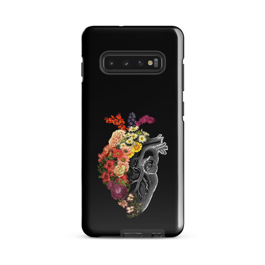 The design is an intricate and anatomical drawing of a human heart on a black background. The left side of the heart morphs into a vibrant assortment of colorful flowers, including roses, daisies, and other blooming blossoms, creating a striking contrast between the realistic and the surreal, symbolizing the harmony between nature and humanity.