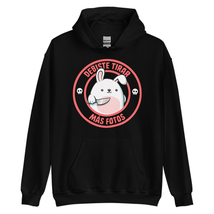 A cute white cartoon bunny with a pink belly stands holding a large kitchen knife in one paw. Surrounding the bunny is a red circular border with the words 'DEBISTE TIRAR MÁS FOTOS'. Small skull icons are on either side of the circle. The overall tone is a mix of adorable and ironic humor.