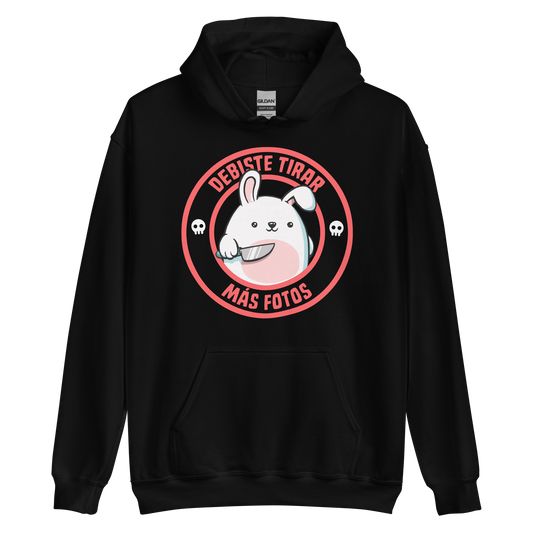 A cute white cartoon bunny with a pink belly stands holding a large kitchen knife in one paw. Surrounding the bunny is a red circular border with the words 'DEBISTE TIRAR MÁS FOTOS'. Small skull icons are on either side of the circle. The overall tone is a mix of adorable and ironic humor.