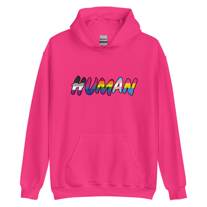 The image displays the word 'HUMAN' in bold, capitalized letters filled with colorful pride flag patterns. The colors within the letters represent different LGBTQ+ pride flags, symbolizing inclusivity and diversity. The background is solid black, which makes the colorful patterns stand out more vibrantly.