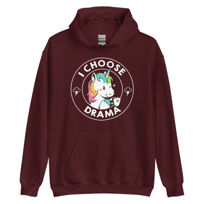 A cartoon unicorn with rainbow-colored mane holds a cup of tea and a heart, encircled by the words 'I Choose Drama'. Two small clouds with lightning bolts flank the unicorn, adding a playful yet slightly edgy vibe. The design is bold and whimsical with a pop-art influence.