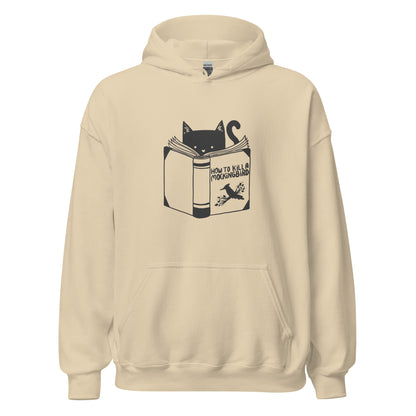 A black and white illustration features a cat peeking over an open book titled 'How to Kill a Mockingbird,' playfully altering the classic novel's title. The cat has a heart-shaped nose and simple, cute facial features. The design is whimsical and ironic, combining classic literature with a humorous twist.