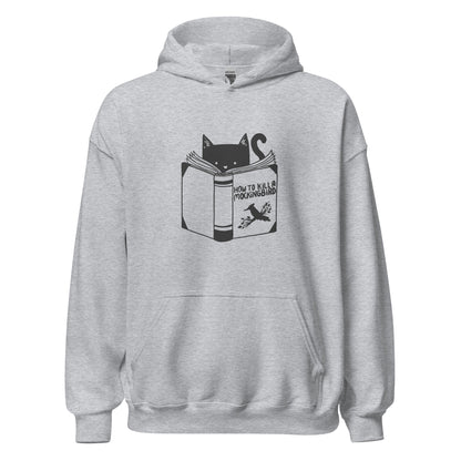 A black and white illustration features a cat peeking over an open book titled 'How to Kill a Mockingbird,' playfully altering the classic novel's title. The cat has a heart-shaped nose and simple, cute facial features. The design is whimsical and ironic, combining classic literature with a humorous twist.